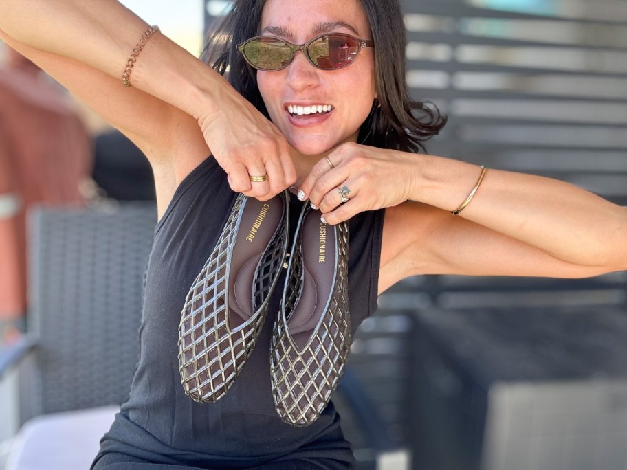 woman holding a pair of black jelly sandals