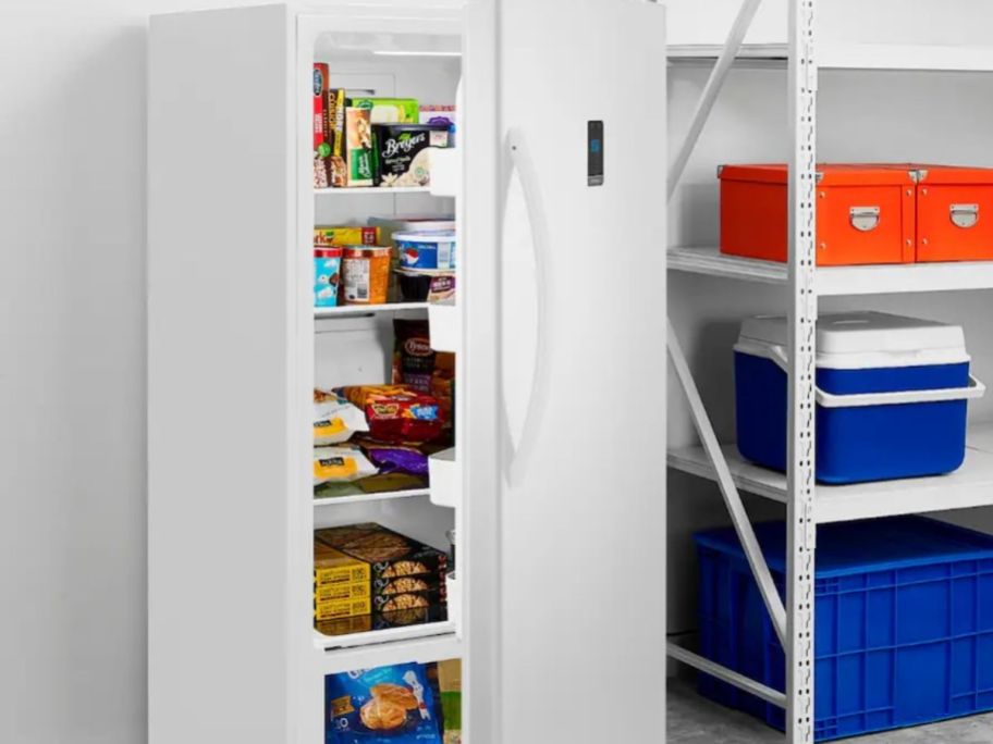 Insignia upright freezer with items inside displayed in a garage