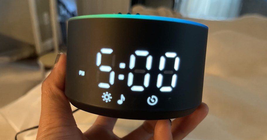 person holding a black alarm clock