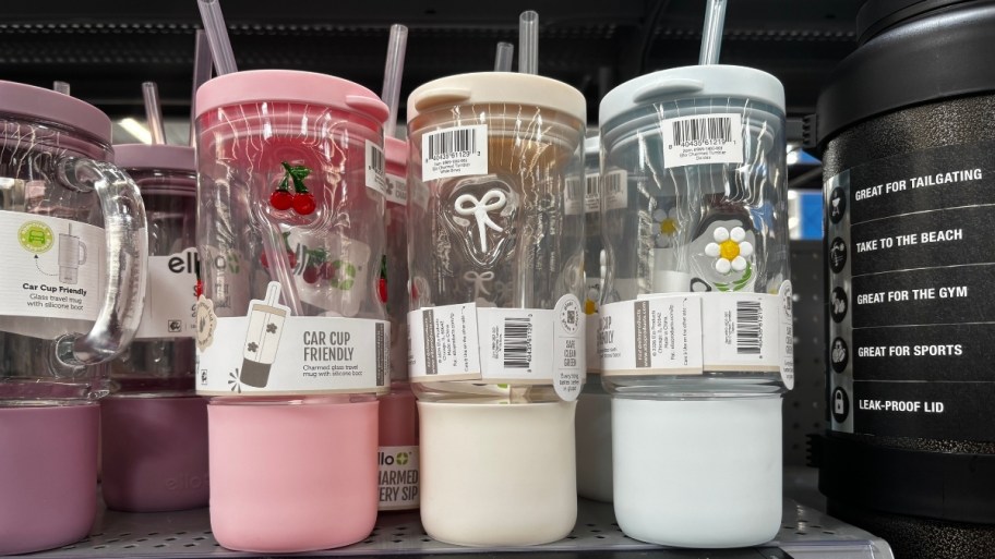 three glass tumblers with boots straws and lids on a store shelf