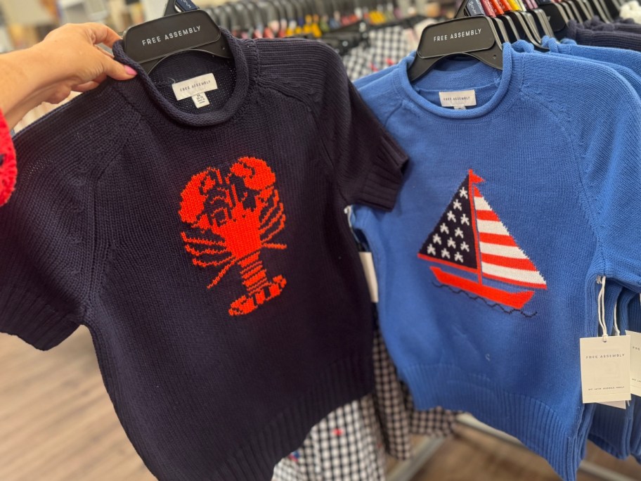 two patriotic sweaters on hangers at Walmart