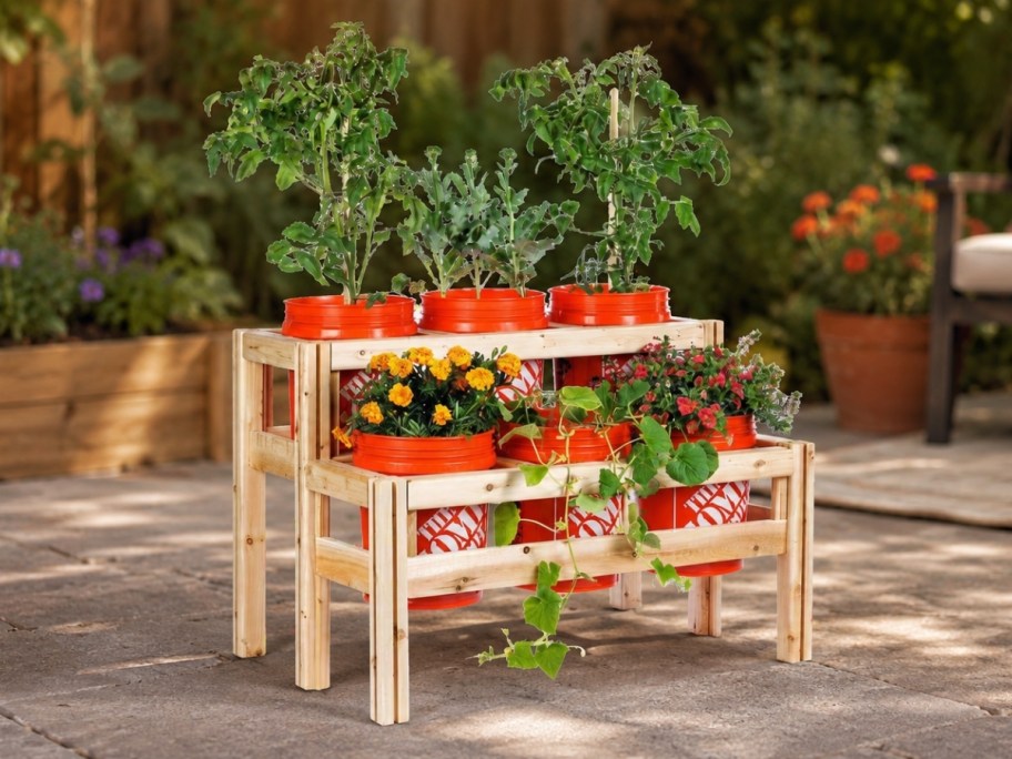 2 tier 6 bucket cedar raised garden bed frame with ornage buckets, filled with plants on a patio