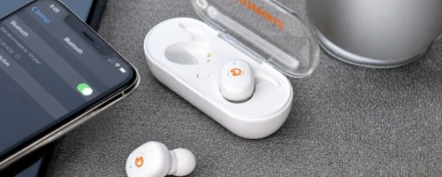 a pair of earbuds with the charging case next to a smartphone