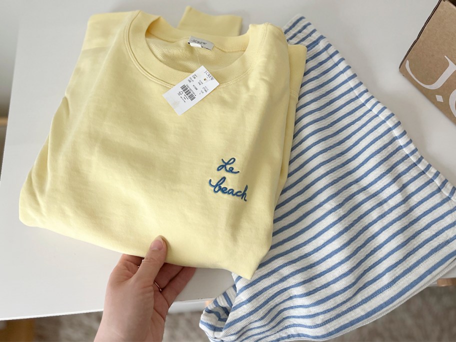 hand reaching for yellow la beach and blue and white striped shorts 