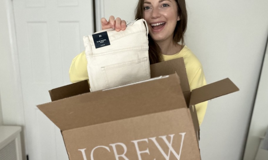 a woman holding a jcrew shipping box and pants