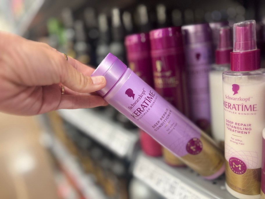 hand pulling a bottle of conditioner off a store shelf