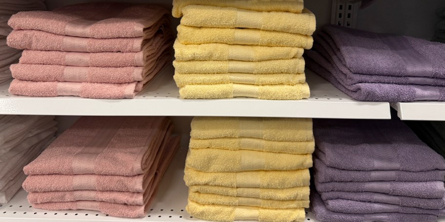 pink, yellow and purple towels stacked on shelf 