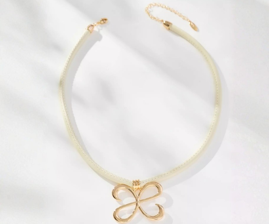 chocker necklase with a gold pendant on a white cord