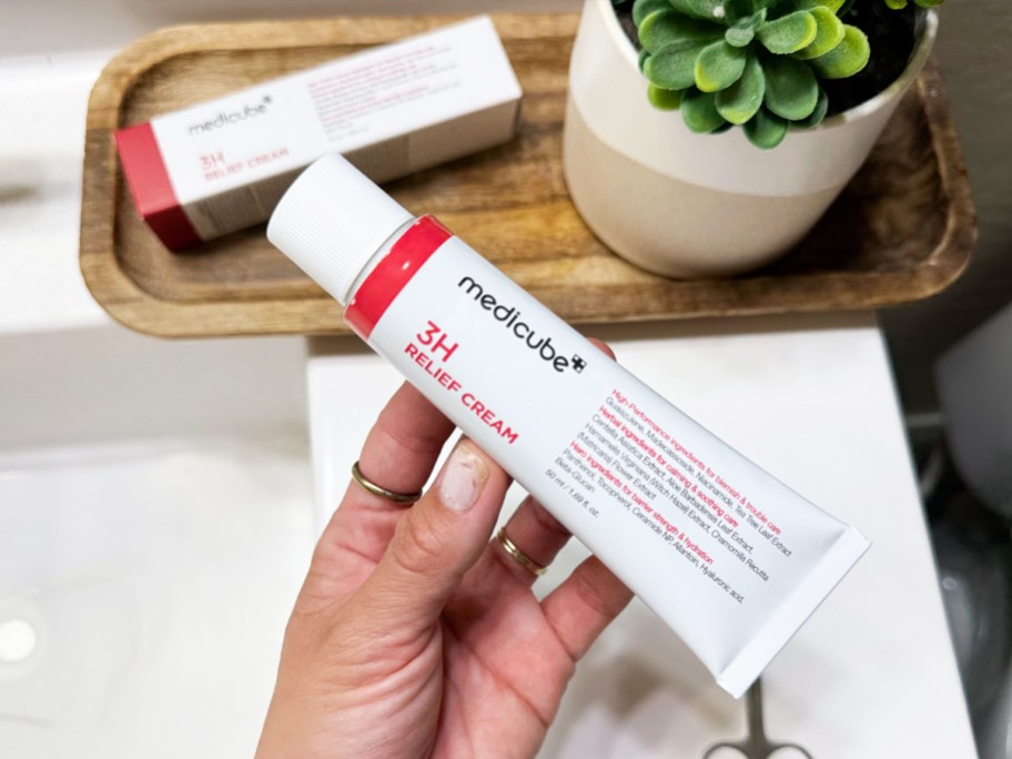 hand holding a white tube of medicube 3H Daily Relief Cream