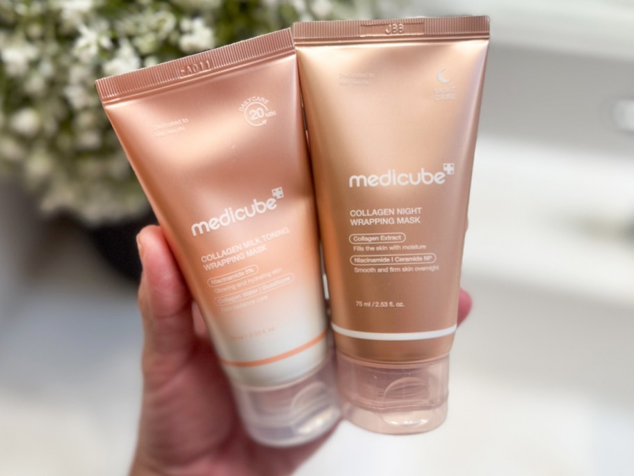 hand holding two pink tubes of medicube Collagen Masks