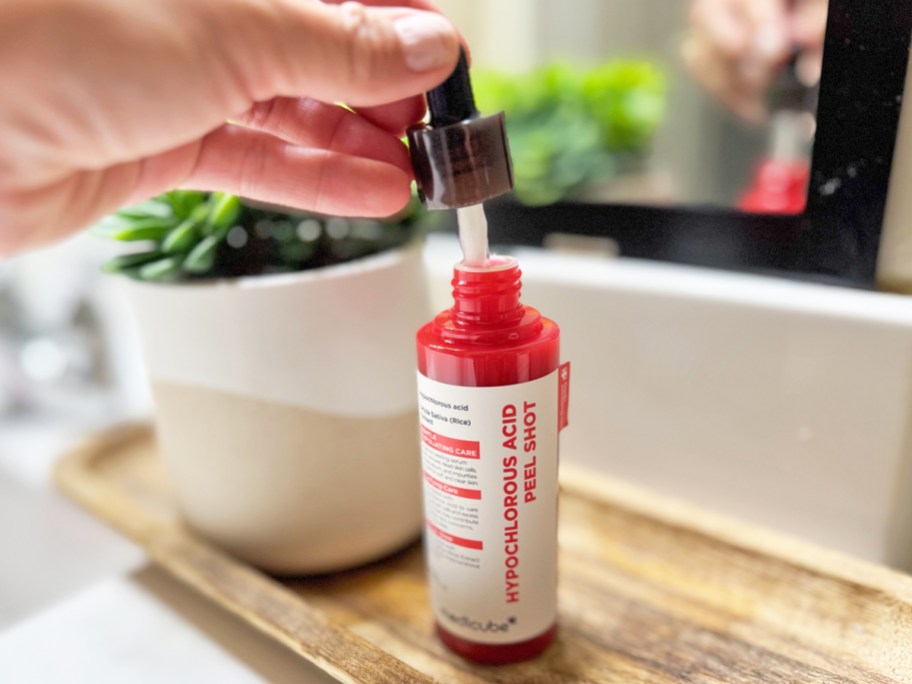 hand holding dropper to medicube Hypochlorous Acid Peel Shot bottle