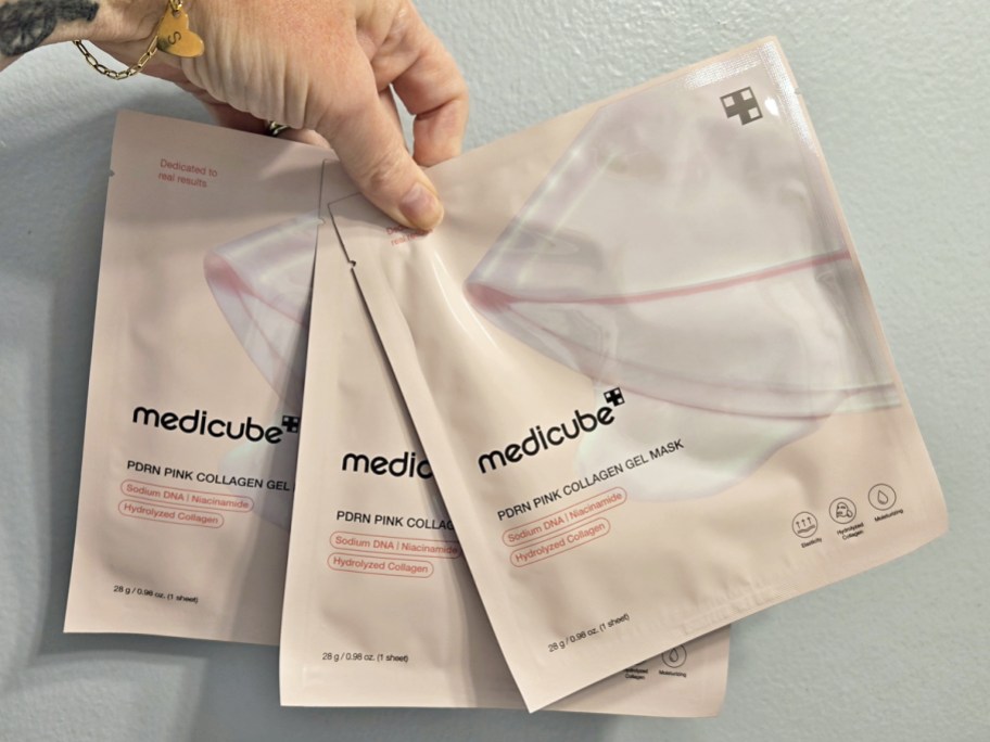 hand holding 3 medicube PDRN Pink Collagen Gel Masks