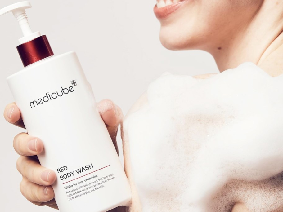 woman holding white bottle of medicube Red Body Wash