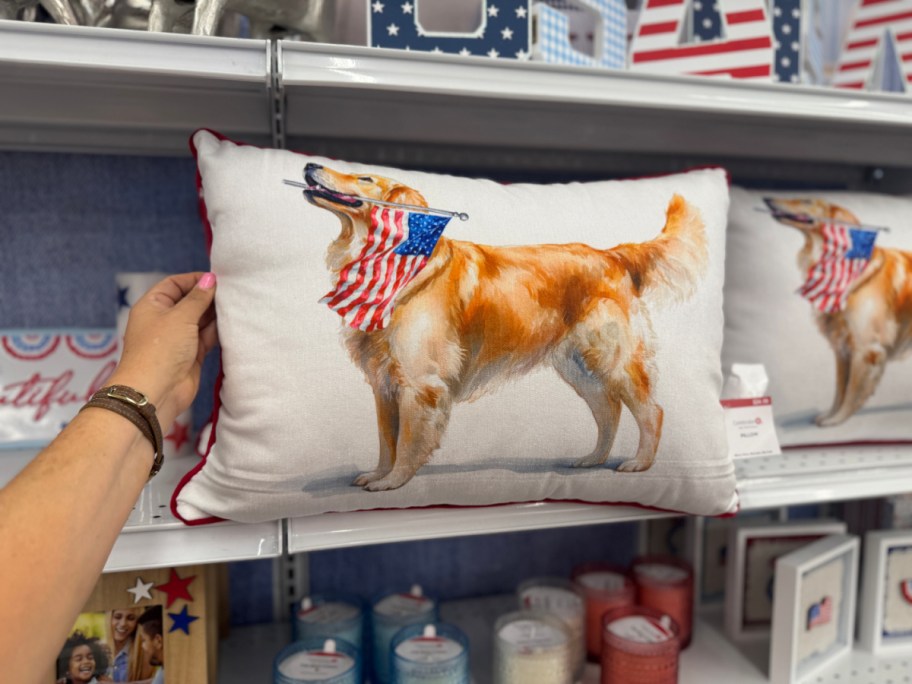 A decorative pillow depicts a golden retriever holding an American flag in its mouth.