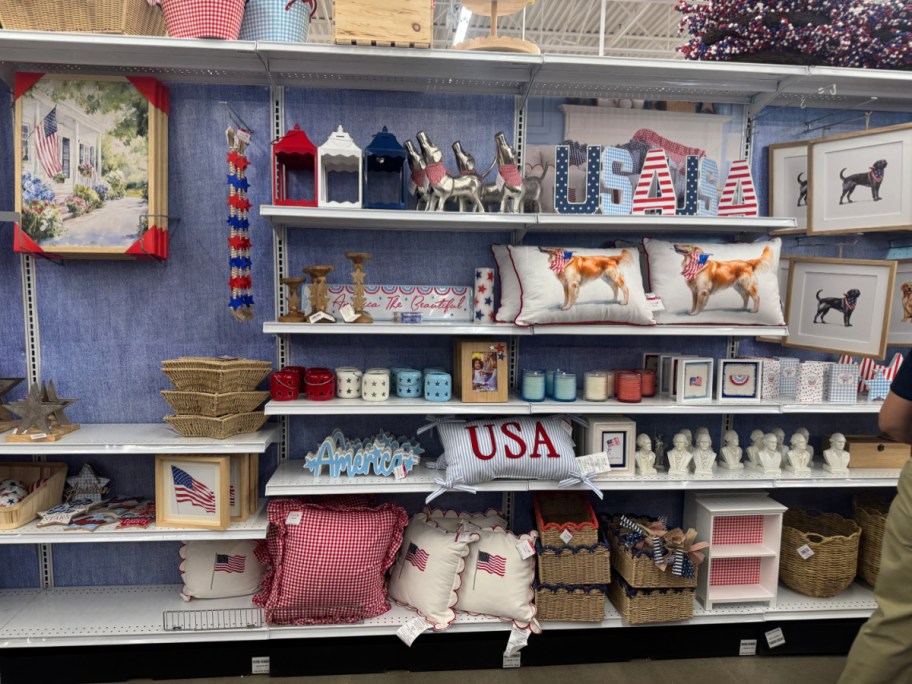 Shelves display patriotic USA decor with red, white, and blue items. Highlights include USA letters, dog-themed pillows, candles, and American flags.