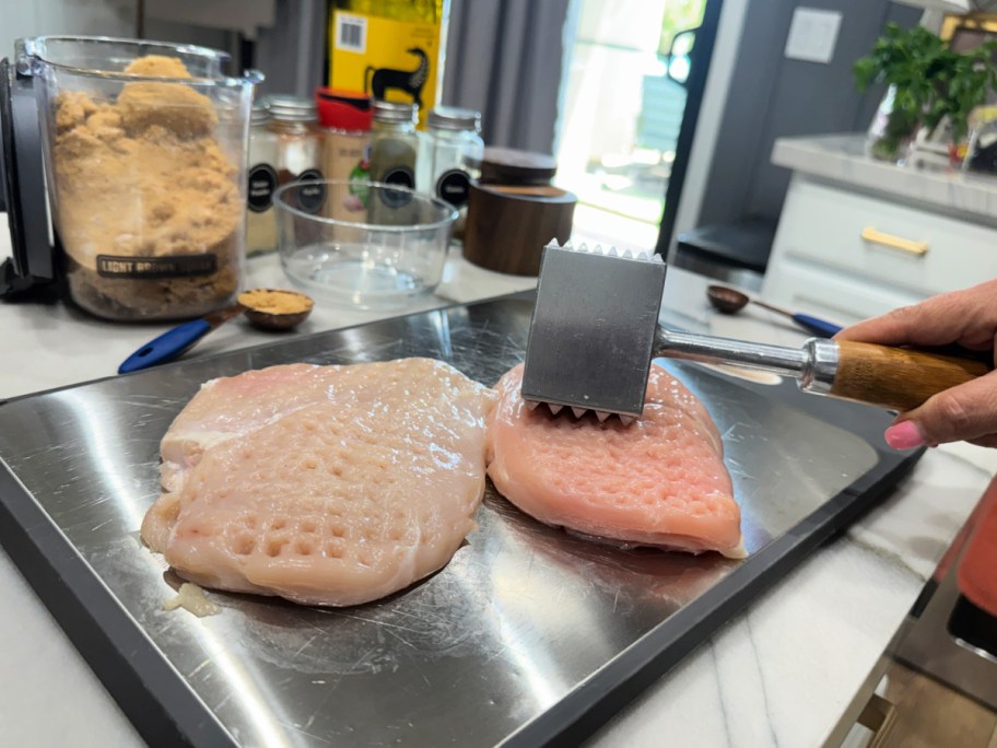 pounding chicken on a cutting board 