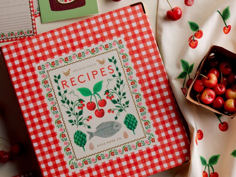 red cookbook next to basket of cherries