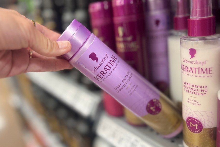 hand grabbing purple haircare off shelf