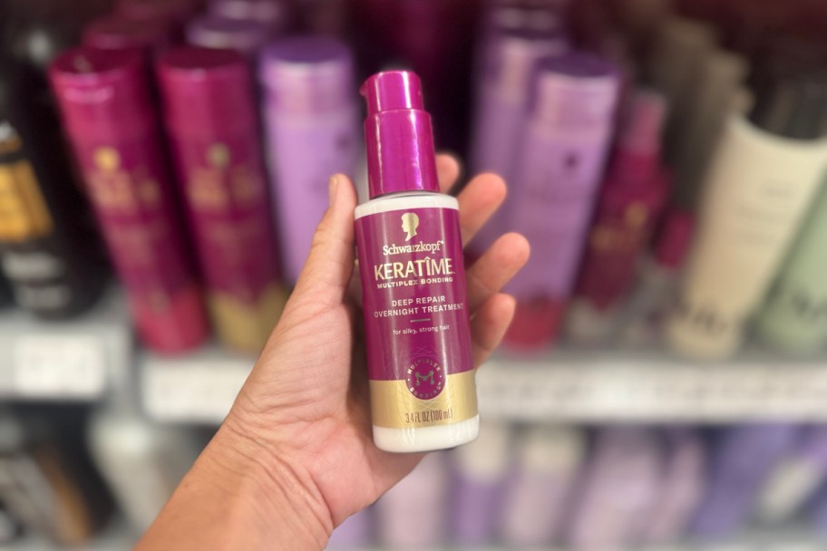 hand holding small purple spray bottle