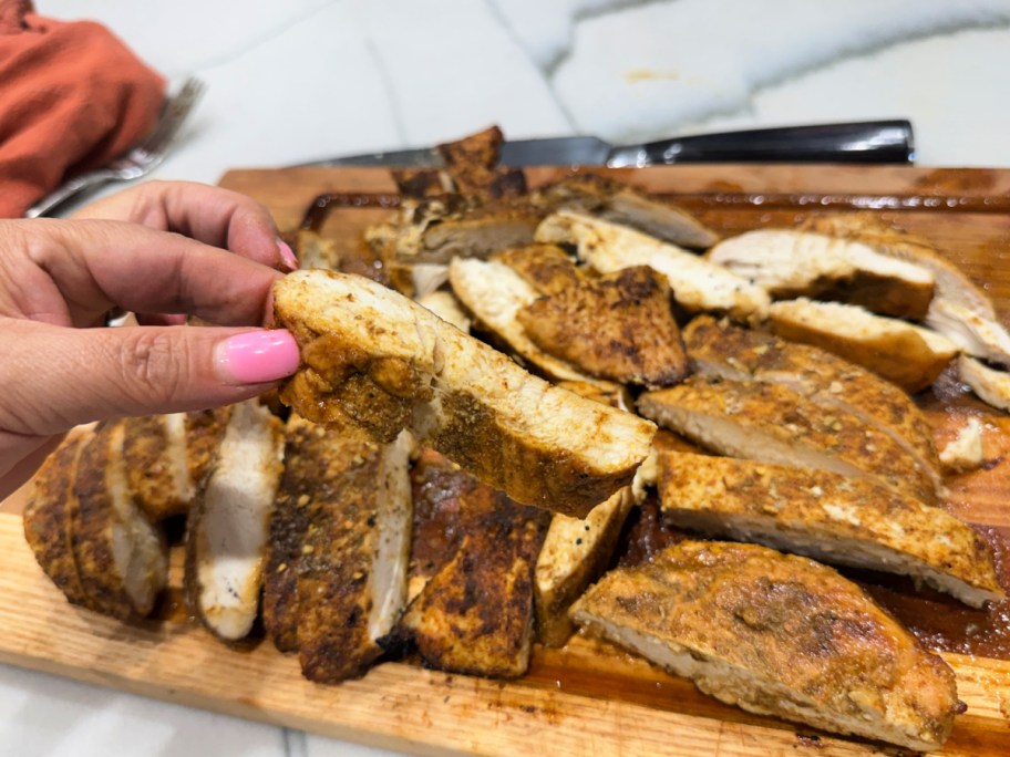 slicing up juicy baked chicken on a cutting board