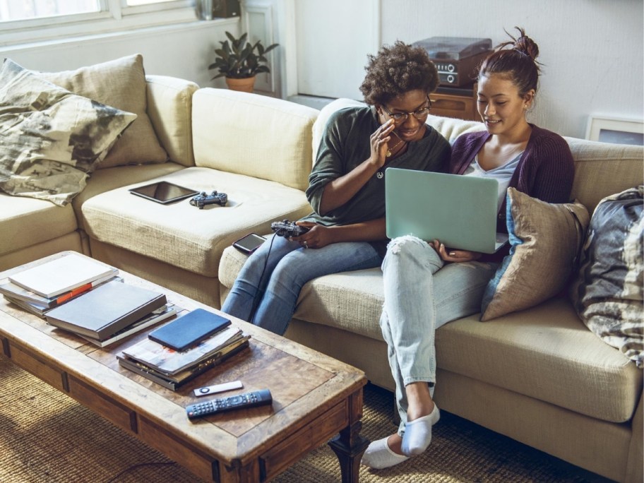a man and woman sitting on a sofa looking at a laptop