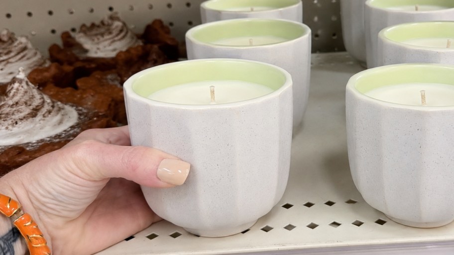 womans hand reaching for a candle from a store shelf