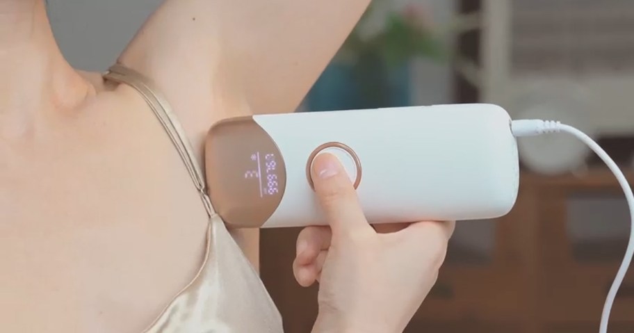 woman using laser hair remover on underarms