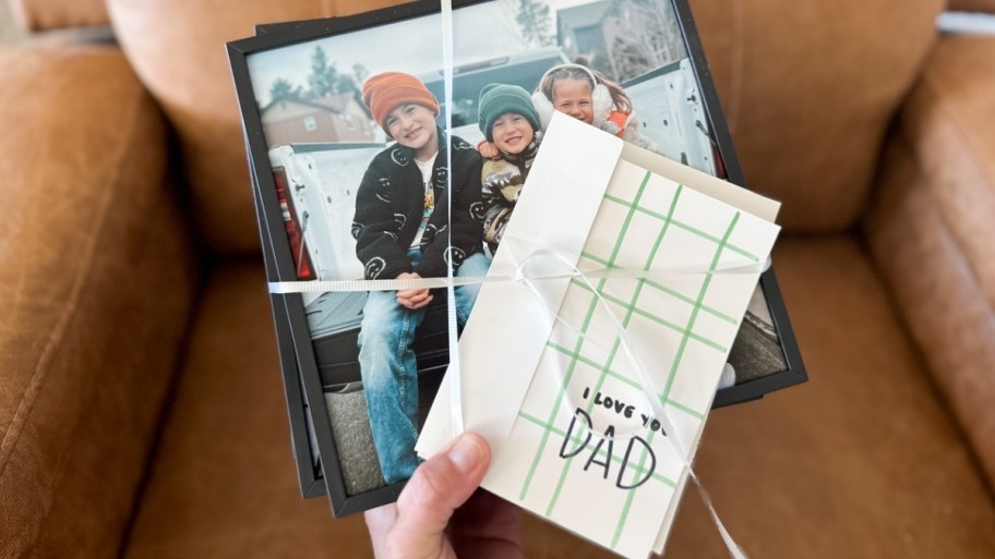 womans hand holding stack of tilepix tied with ribbon and a fathers day card