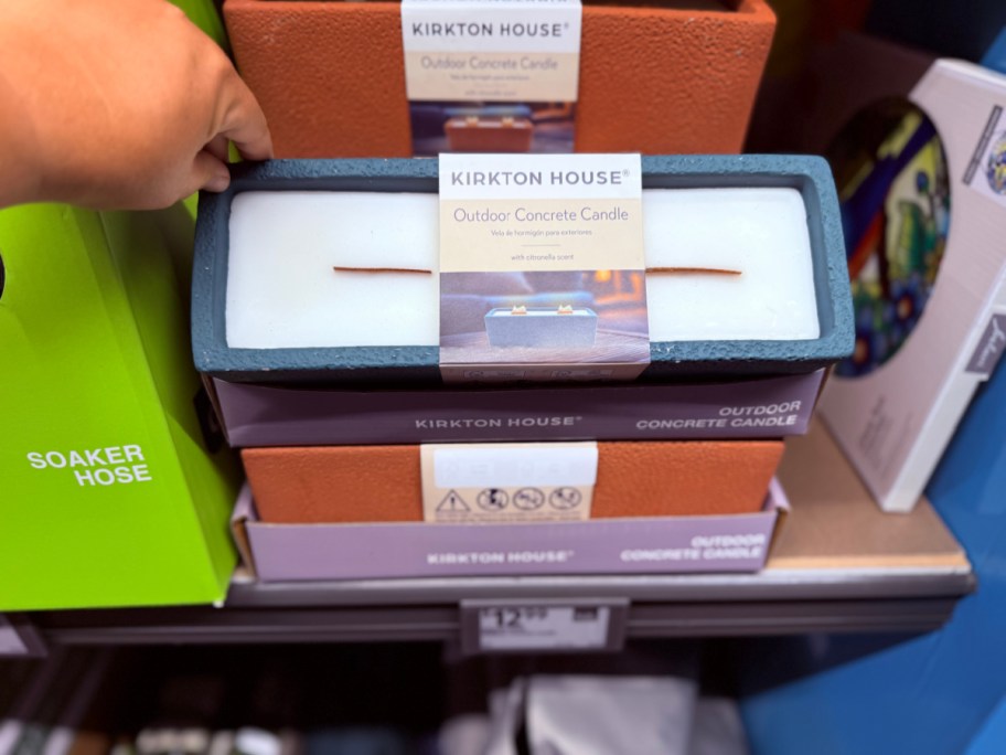 hand grabbing rectangular concrete candle on shelf