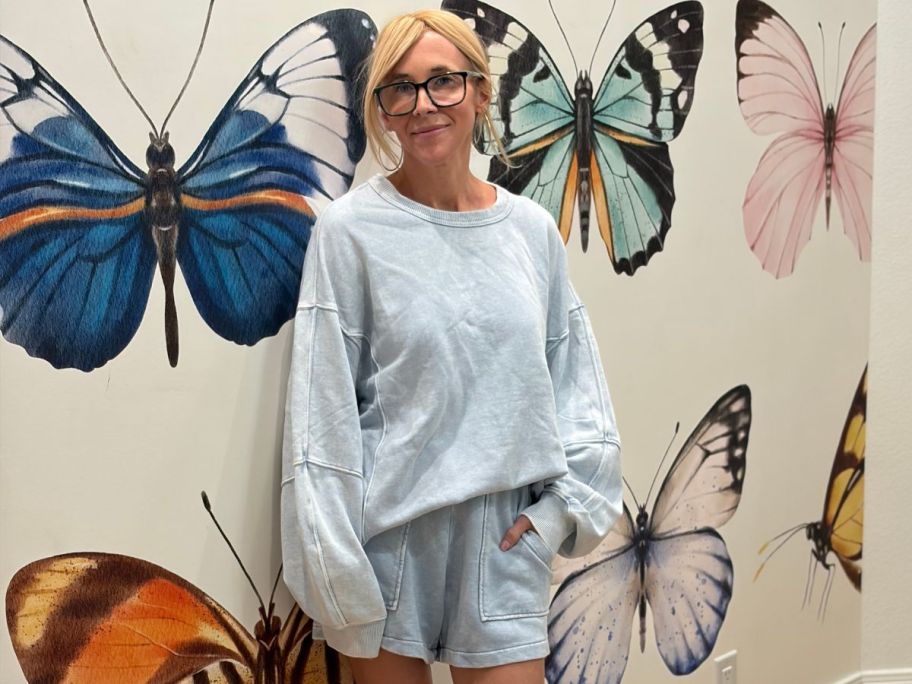 Woman wearing a lightwash denim blue sweatshirt and shorts from Aerie