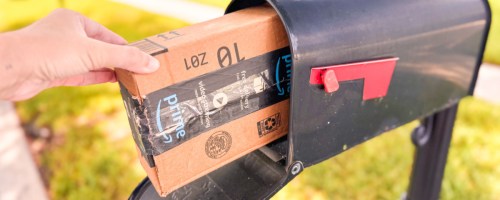 Hand taking Amazon prime box out of black mailbox