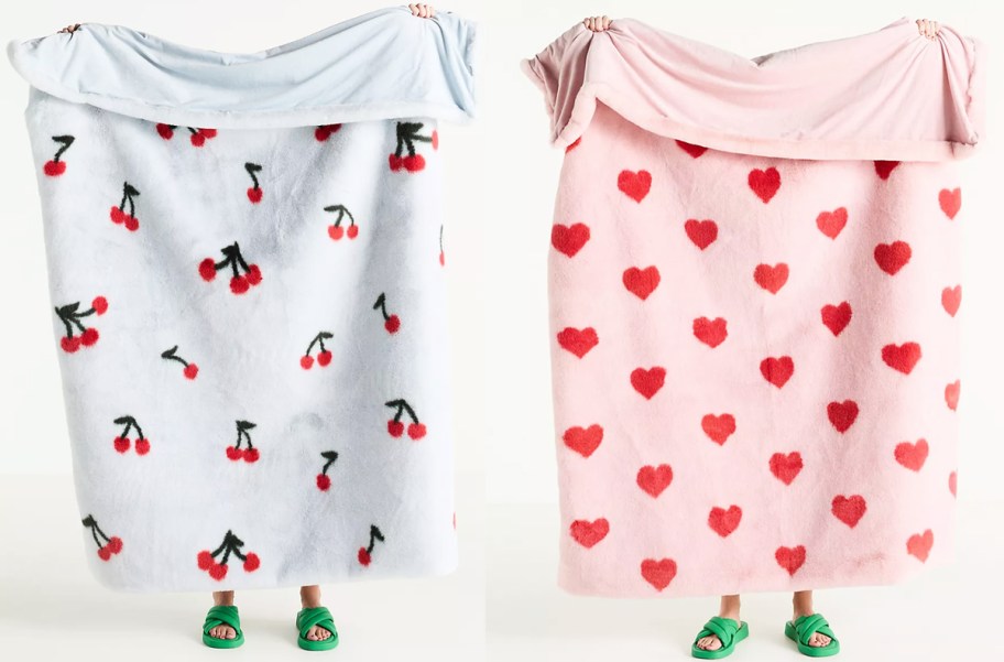 two people holding up cherry and heart print blankets