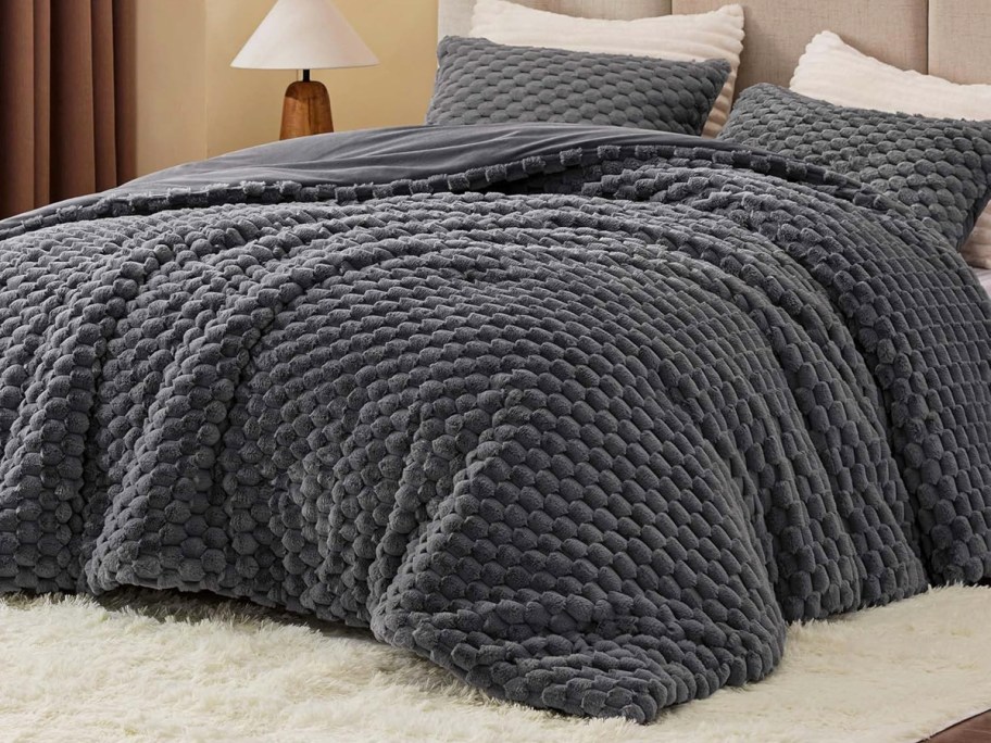 grey fluffy comforter and shams on a bed
