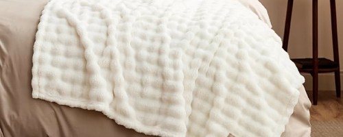 white throw blanket draped over a bed