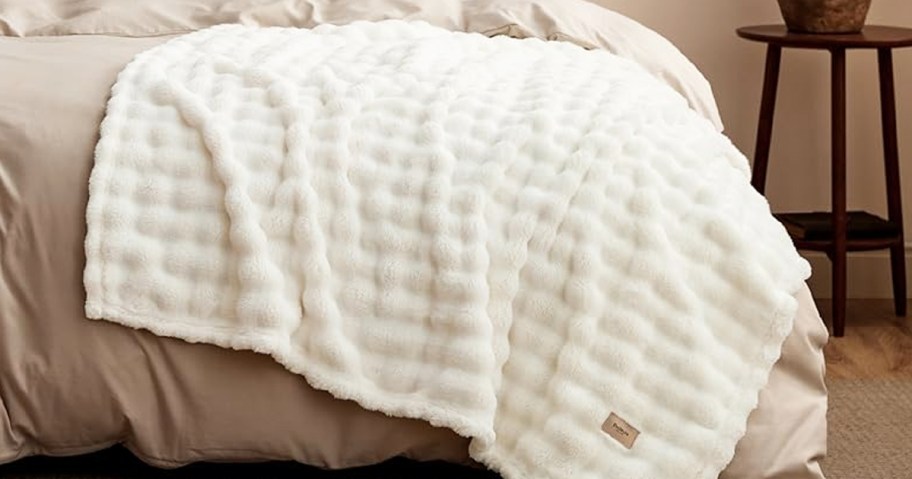 white throw blanket draped over a bed