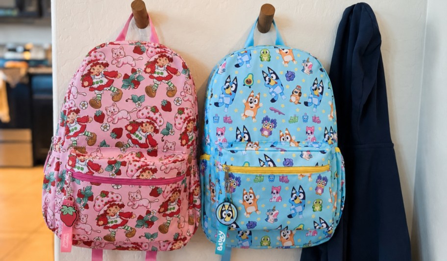 Strawberry shortcake and Bluey character backpacks hanging on hook