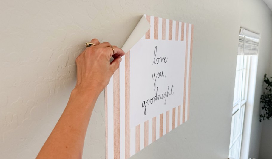 hand applying a CVS photo poster to a wall