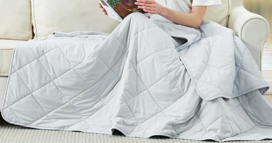 person sitting on couch under a grey blanket
