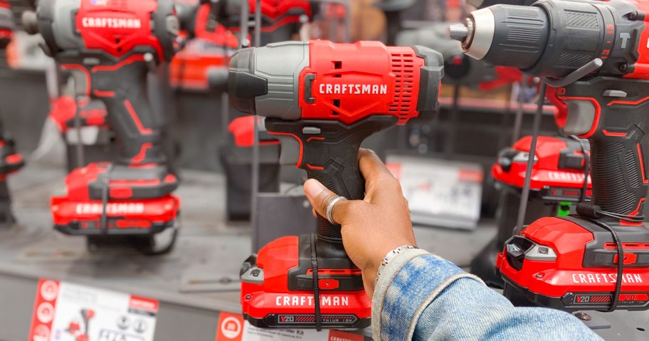 hand touching a red and black Craftsman drill on display in store