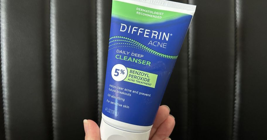 Hand holding a tube of Differin Acne Cleanser