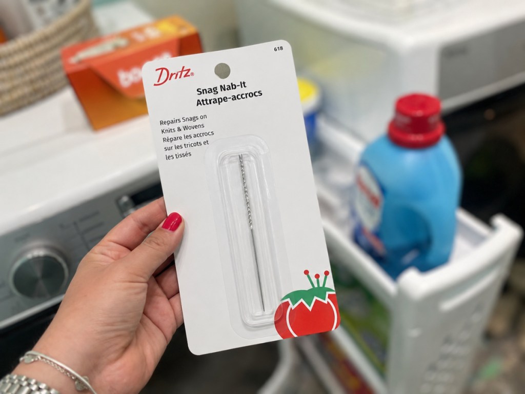hand holding Dritz Snag Nab-It in laundry room