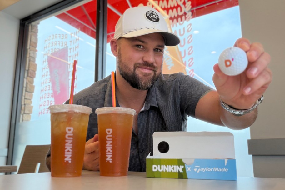 Man sitting behind Dunkin drinks and a Munchkin golfball sleeve