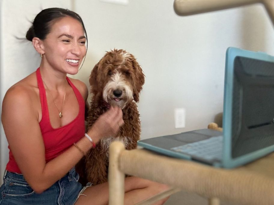 Woman with a dog sitting in front of a laptop