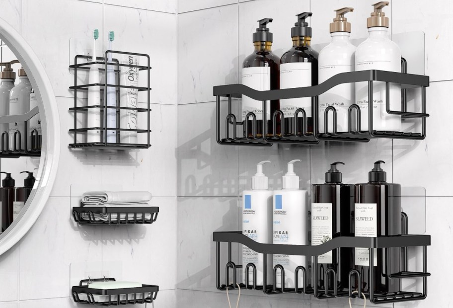 A modern bathroom shelf system made of black metal, featuring multiple baskets that hold various bottles and containers of toiletries, along with a round mirror on the wall.
