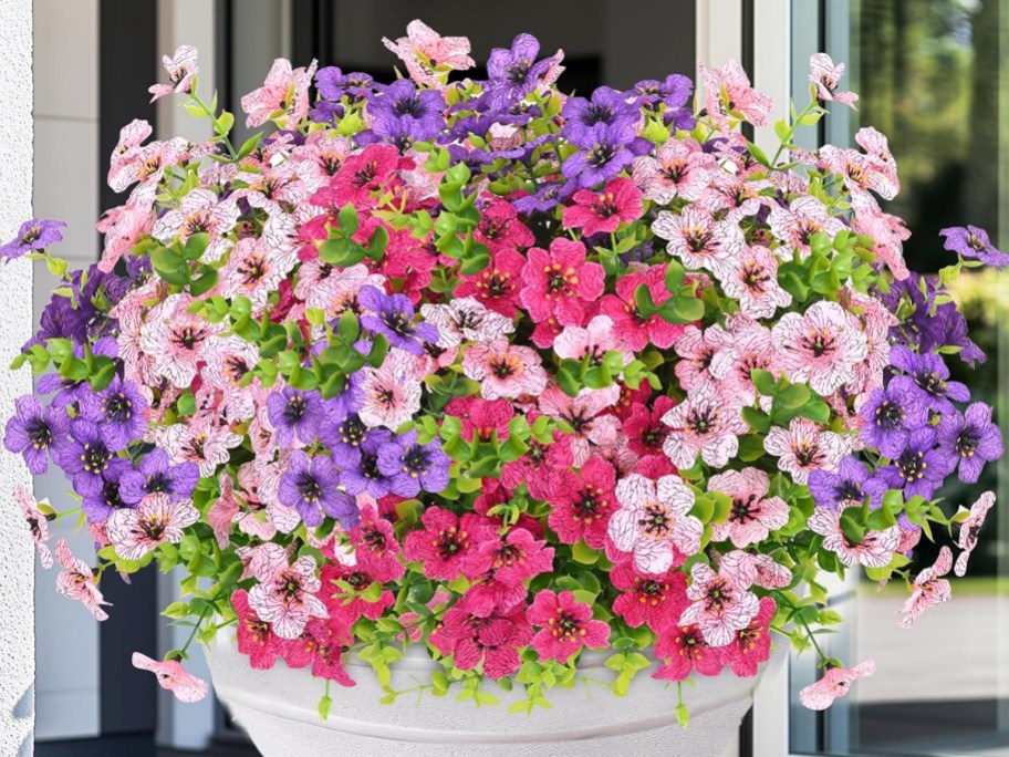 light pink, dark pink, and purple artificial flowers in a white planter