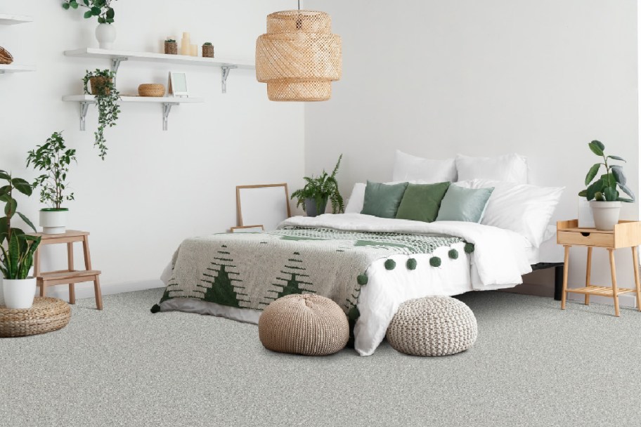 A bed with green and white bedding in a bedroom decorated with natural wood, green and white decor
