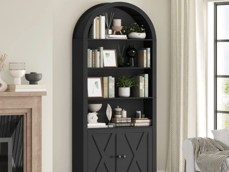 black arched cabinet filled with books and decor