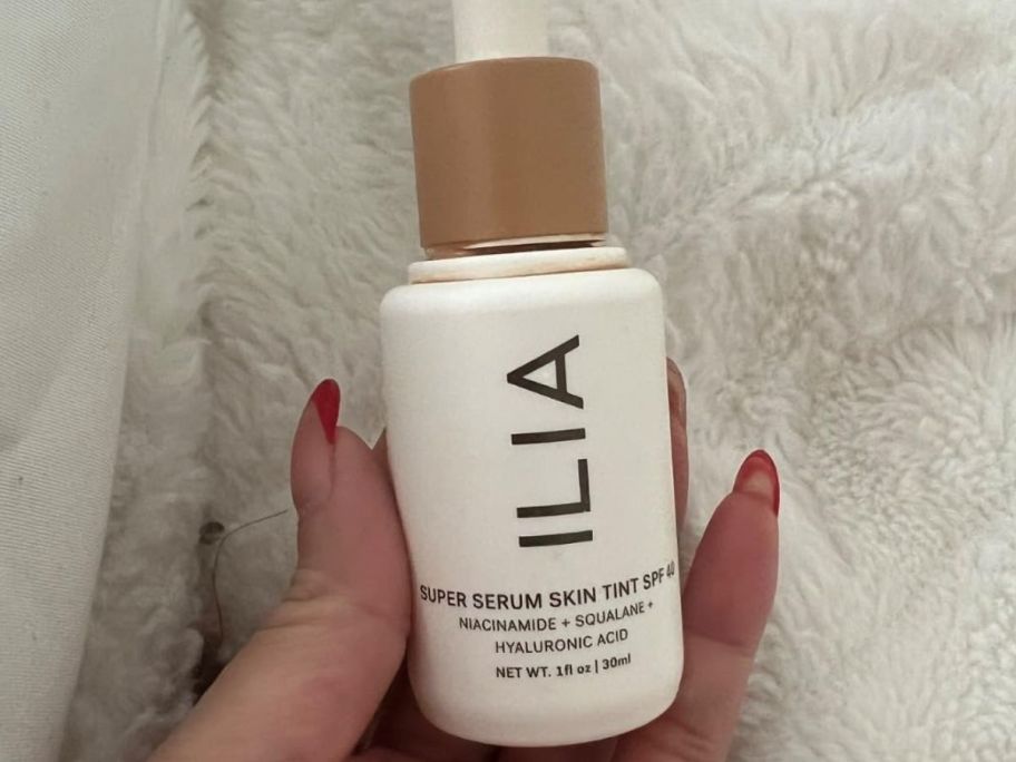 Hand holding a bottle of Ilia Super Serum SKin Tint