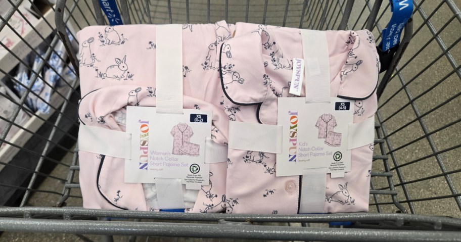 A shopping cart containing folded clothing with a pastel pink fabric featuring a bunny print.