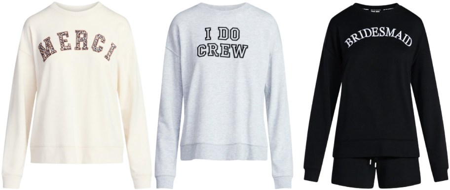 Three sweatshirts displayed side by side: a cream sweatshirt with "MERCI" in decorative letters, a light blue sweatshirt with "I DO CREW" text, and a black sweatshirt with "BRIDESMAID" in bold lettering.